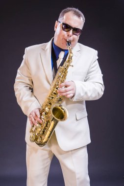 Müzik Temalar ve fikirler. Siyah Background.Vertical görüntü yönü karşı sakin beyaz olgun saksofoncu