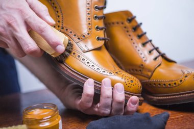 Ayakkabı fikirler. Profesyonel erkek ayakkabı ile Cleaner temizlik fırça için Tan Derby çizme elleri. Mavi önlük atölyesinde çalışıyor. Yatay atış