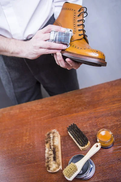 Portre profesyonel erkek ayakkabı temizleyici kullanarak kumaş için Tan Derby çizme eller. Atölyesinde çalışıyor. Dikey görüntü kompozisyon