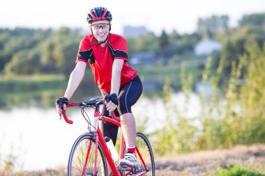 Mutlu gülümseyen erkek bisikletçi bir dinlenme ve davlumbaz elleriyle bisikletle poz. Açık Shot.Horizontal resim kompozisyon