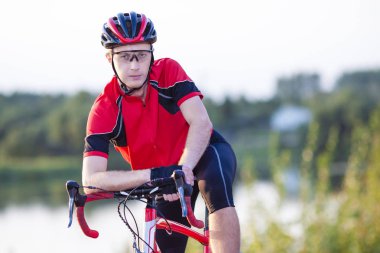 Erkek bisikletçi portresi bir dinlenme ve bisikletle poz. Açık Shot.Horizontal resim kompozisyon