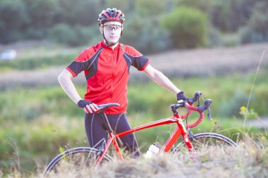 Açık havada doğa arka plan üzerinde poz yol bisikleti ile adam bisikletçi portresi. Profesyonel kıyafeti ile donatılmıştır. Yatay yönlendirme