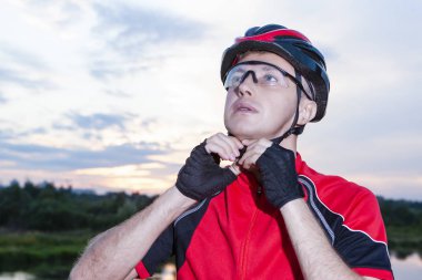 Açık havada, altın Hour.Horizontal görüntü kompozisyon erkek bisikletçi sabitleme onun koruyucu kask