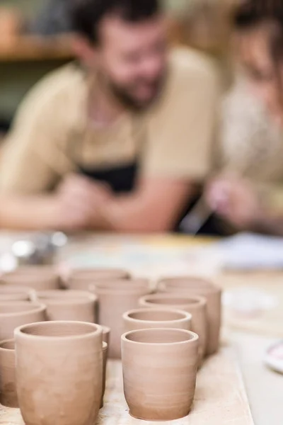 Two Ceramists Decorating Clay Crafts In workshop. Blurred Background. Vertical image