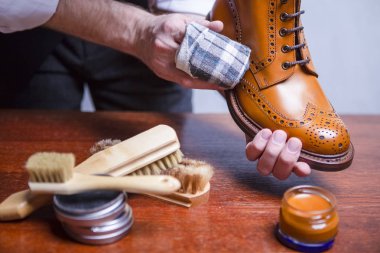 Ayakkabı Bakım fikirler. Closeup ile temizlik bezi Tan yüksek Derby çizme parlatma için kullanılır elleri Mans. Bir sürü fırçaları çerçeve içinde. Stüdyo çekim. Yatay atış