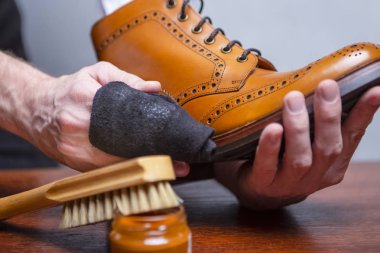 Lüks ayakkabı fikirler. Closeup ile temizlik bezi parlatma ve yedirme Tan yüksek Derby Boots için kullanılır elleri Mans. Stüdyo Shot.Horizontal kompozisyon
