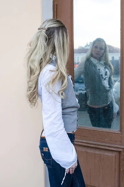 Youth Outdoors Concepts. Young Sensual Caucasian Female in Front of Mirror Reflecting Door.Posing in Casual Wear.Vertical Image
