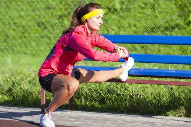 Spor kavramları. Bacak kasları Stretchings katlanmış elleriyle sahip açık spor kıyafeti beyaz sporcumuz yoğunlaşmıştır. Kulaklık müzik dinlemek. Yatay atış