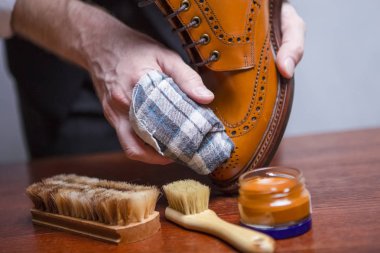 Mens ayakkabı bakım fikirler. Closeup ile temizlik bezi Tan yüksek Derby çizme parlatma için kullanılır elleri Mans. Stüdyo çekim. Yatay resim kompozisyon