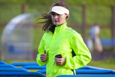 Koşu ve kavramlar çalışıyor. Açık Eğitim sırasında profesyonel kadın Runner portresi. Güneşlik giymek ve çalışırken müzik dinlemek. Yatay görüntü