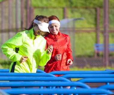 İki pozitif ve gülümseyerek beyaz Sportswomen birlikte eğitim koşu sahip açık kıyafeti. Eğitim engel Course.Horizontal görüntü üzerinde