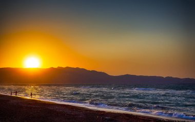 Girit Adası Yunanistan Kandiye sahilde güzel günbatımı şaşırtıcı. Deniz kıyısı boyunca insanlar Wakling siluetleri. Yatay resim kompozisyon