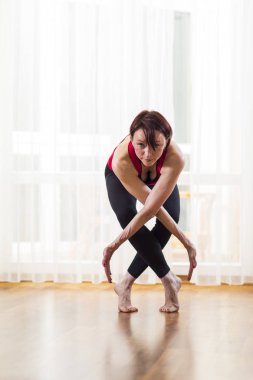 Kafkas kadın Yoga Asana kapalı büyük güneşli pencerenin önünde pratik yoğunlaşmıştır. Ayakta ile geçti içinde Front.Posing içinde terapi poz verdi. Dikey kompozisyon