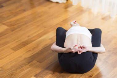 Beyaz sportif kadın yapıyor pratik Yoga kapalı. Arkada oturan ve Exercises.Horizontal görüntü uzanan bacaklar