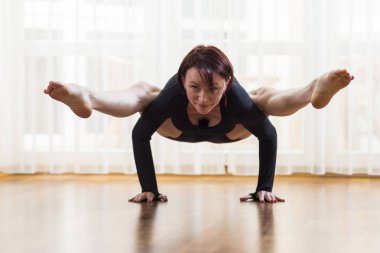 Positivecacuasian kadın Yoga Tittibhasana duruş kapalı yapıyor. Horizointal kompozisyon