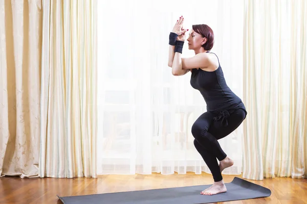 Yoga Concept Caucasian Woman Practicing Yoga Exercise Indoors At Bright Afternoon Standing In Garudasana Pose During Solitude Meditation Session Wearing Black Top Bra And Black Leggings Horizontal Shot Stock Images Page
