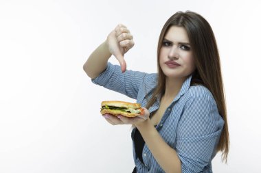 Fastfood kavramı yeme. Burger ve başparmak işareti aşağı Studio yeme genç beyaz kadın. Çizgili gömlek Indoors.Horizontal görüntü kompozisyon poz