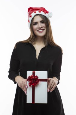 Noel fikirler. Noel Baba şapkası önünde kırmızı kurdele ile sarılmış beyaz hediye kutusu ile beyaz kadın poz portresi. White.Vertical görüntü yönünü karşı