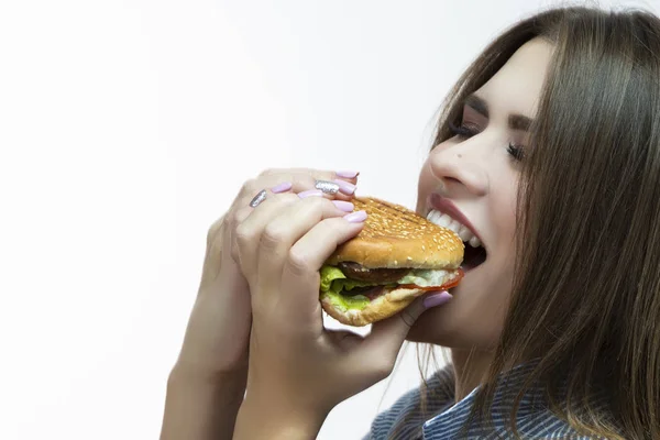 Unhealthy Eating Concepts. Closeup of Caucasian Woman Eating Burger. Profile Face View. Posing in Striped Shirt Indoors in Studio. Horizontal Image Composition