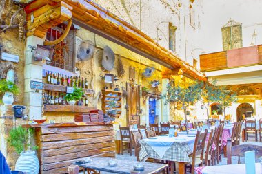Klasik Cretan açık hava restoranı Chania hizmet tablo ve sanatsal dekore edilmiş duvarlar. Yatay görüntü