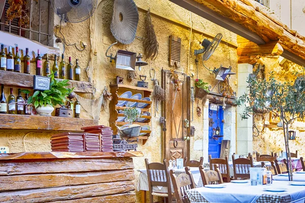 Klasik Cretan açık hava restoranı Chania hizmet tablo ve sanatsal dekore edilmiş duvarlar. Yatay görüntü