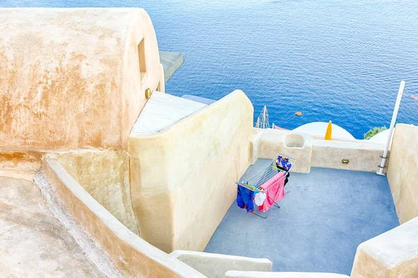 Oia Village pale Houses with Linen Hanged for Drying Outdoors with Sea on Background.Horizontal Image