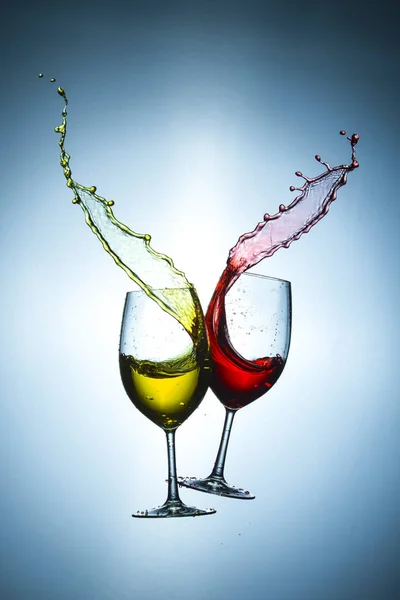 Two Types of Wine Splashes Poured Out from Glasses Against Bluish Background. Short Flash Duration for Freezing Motion Used. Vertical Image Composition