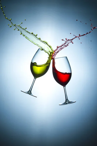 Two Types of Wine Splashes Poured Out from Glasses Against Bluish Background. Short Flash Duration for Freezing Motion Used. Vertical Image Composition