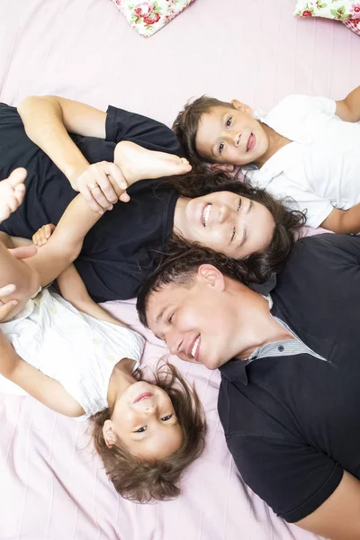 Family Values. Happy Caucasian Family of Four Having Fun While Lying on Sofa Indoors. Vertical Image Orientation