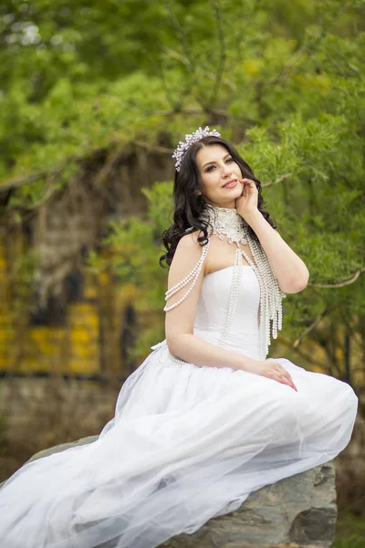 Portrait of Sensual Caucasian Bride With Diadem Sitting On Stone