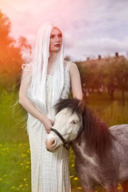 Uzun Beyaz Saçlı Muhteşem Sarışın Kadın Midilli Hors ile Poz