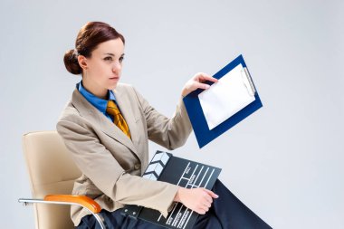 Film yapımcılığı konseptleri. Kendine güvenen profesyonel kadın film yönetmeninin portresi Actioncut ile. Sandalyede otururken Not Defteri 'ni göstererek. Yatay Resim Yönlendirmesi