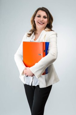 İş Kadınları Konsepti. Beyaz Ceketli, Olumlu ve Gülümseyen Kafkasyalı İş Kadını 'nın Portresi. Beyaz arkaplana karşı renkli klasörlerle poz vermek. Dikey çekim