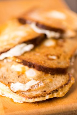 Kızarmış yumurtalarla birlikte çok sayıda geleneksel kızarmış ekmek dilimleri. İçerideki ahşap tahtanın üzerinde. Arazinin derinliği sığ. Dikey Resim