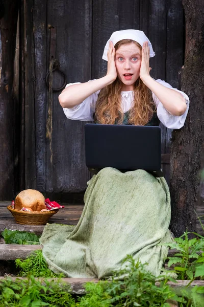 Natural Portrait of Surprised Country Redhaired Girl Working with Laptop in Village Outdoors. Vertical Image