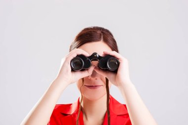 Beyaz arkaplana karşı dürbünlü esmer kız pozu veren beyaz kız portresi. Yatay Çekim