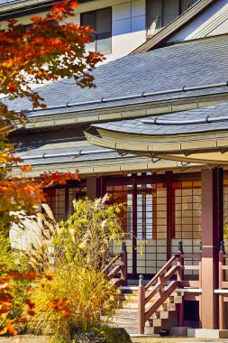 Japon mirası. Japonya 'daki Kutsal Koyasan Dağı' ndaki Manastır Kapıları 'nın önünde mevsimlik Kızıl Akçaağaç. Dikey Görüntü Kompozisyonu