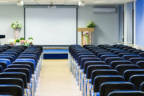 Contemporary Interior of Empty Conference Room With Blue Chairs in Front of Stage with Screen.Horizontal Shoot