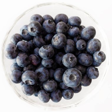 beyaz zemin üzerinde bir kasede yaban mersini.