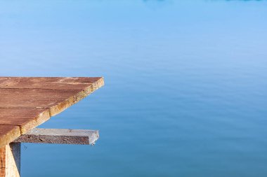 Göl veya göl üzerinde bir iskele. Sudan arkaplan. Platform ve tahtalar. Güneşli bir sabah. Balıkçı konumu.