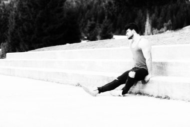 Siyah kot - kaslı atletik vücut Fitness Model açık havada - bir yer, metniniz için poz giyen süre ayakta güçlü kasların esneme sağlıklı genç adam