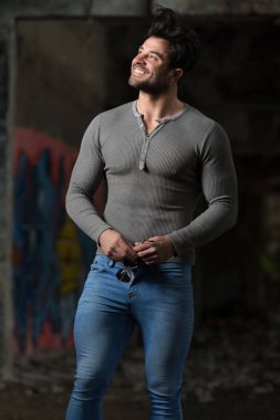 Genç bir portresi fiziksel olarak vücut - kaslı atletik vücut Fitness Model sonra egzersizleri bir Graffiti Duvar önünde poz onun iyi eğitimli gösterilen gri uzun kollu gömlekli adam uygun