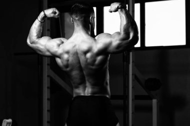 Yakışıklı Genç Adam Spor Salonunda Güçlü Duruyor ve Kaslarını Geriyor - Kas Atletik Vücut Geliştirici Spor Sonrası Spor Pozisyonu