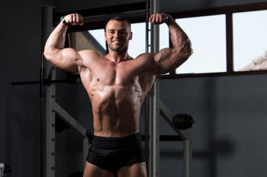 Yakışıklı Genç Adam Spor Salonunda Güçlü Duruyor ve Kaslarını Geriyor - Kas Atletik Vücut Geliştirici Spor Sonrası Spor Pozisyonu
