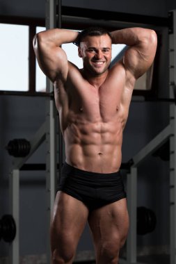 Yakışıklı Genç Adam Spor Salonunda Güçlü Duruyor ve Kaslarını Geriyor - Kas Atletik Vücut Geliştirici Spor Sonrası Spor Pozisyonu