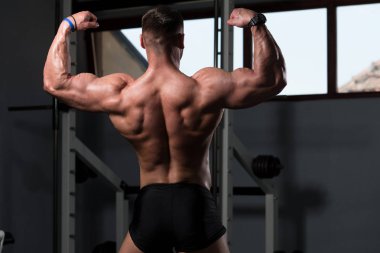 İyi eğitilmiş vücudunu gösteren genç bir adamın portresi - kaslı atletik vücut geliştirici spor sonrası vücut geliştirme modelliği pozu