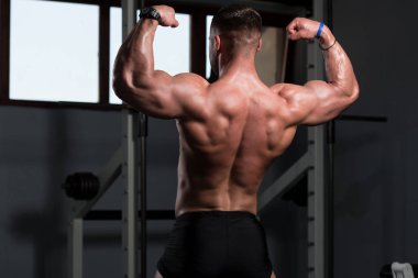 İyi eğitilmiş vücudunu gösteren genç bir adamın portresi - kaslı atletik vücut geliştirici spor sonrası vücut geliştirme modelliği pozu