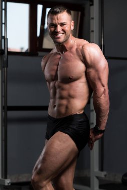 Yakışıklı Genç Adam Spor Salonunda Güçlü Duruyor ve Kaslarını Geriyor - Kas Atletik Vücut Geliştirici Spor Sonrası Spor Pozisyonu