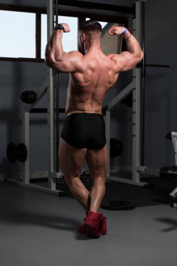 İyi eğitilmiş vücudunu gösteren genç bir adamın portresi - kaslı atletik vücut geliştirici spor sonrası vücut geliştirme modelliği pozu