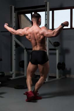 Yakışıklı Genç Adam Spor Salonunda Güçlü Duruyor ve Kaslarını Geriyor - Kas Atletik Vücut Geliştirici Spor Sonrası Spor Pozisyonu
